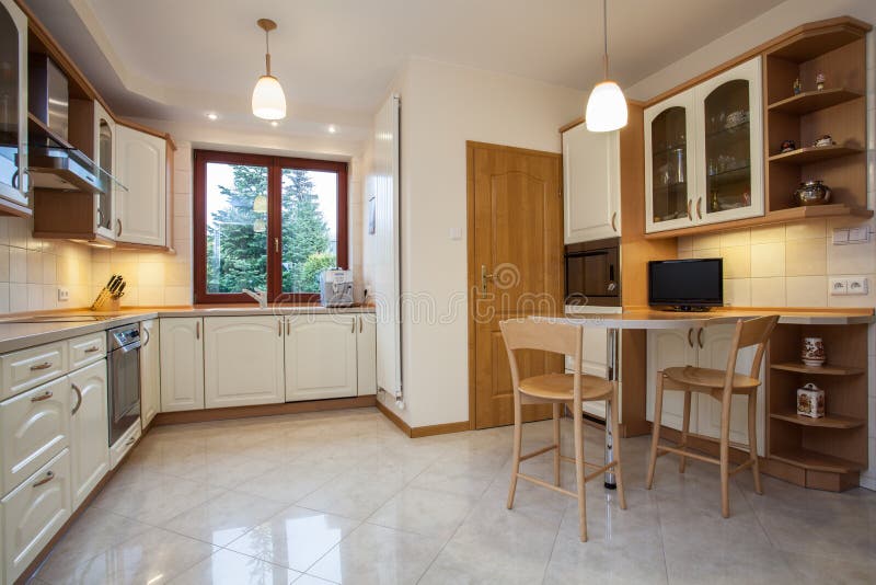 View of traditional kitchen in beige color with television. View of traditional kitchen in beige color with television