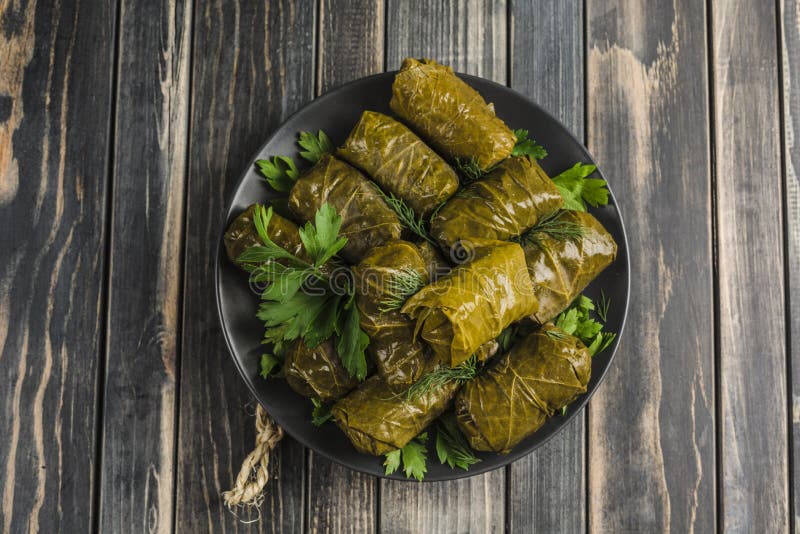 Cucina Mediterranea Dolma di uva farcita di sorte avversa tradizionale deliziosa delle foglie su una banda nera con coriandolo ed fotografia stock libera da diritti Cucina Mediterranea Dolma di uva farcita di sorte avversa tradizionale deliziosa delle foglie su una banda nera con coriandolo ed fotografia stock libera da diritti
