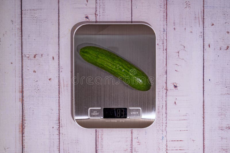 An Cucumber Lies on a Digital Kitchen Scale on a Table of Light Boards