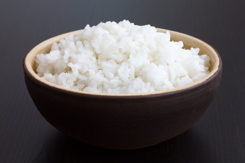 Cuenco rústico de arroz blanco cocinado en superficie oscura