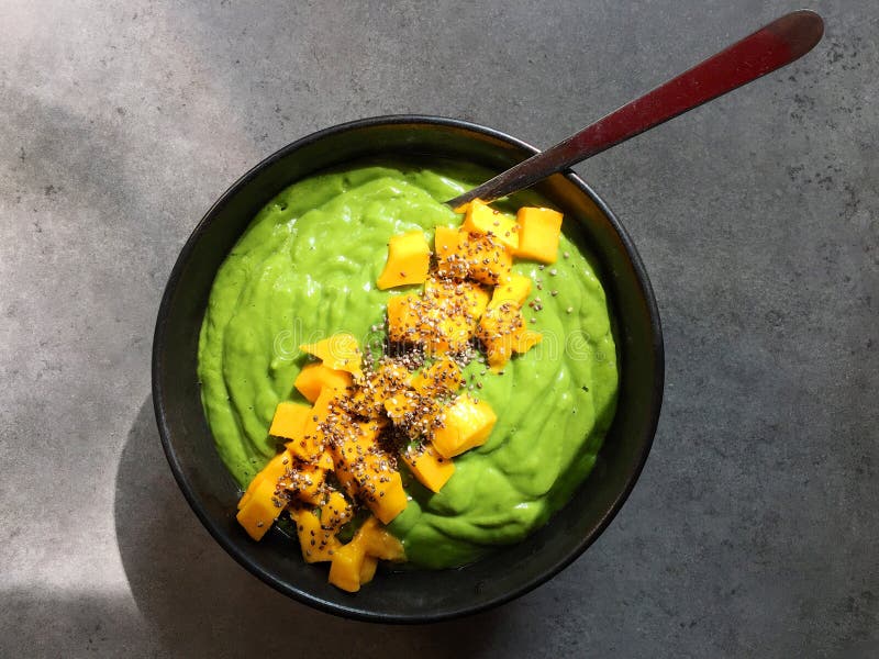 Cuenco verde del smoothie con las semillas tajadas del mango y del chia foto de archivo libre de regalías Cuenco verde del smoothie con las semillas tajadas del mango y del chia foto de archivo libre de regalías