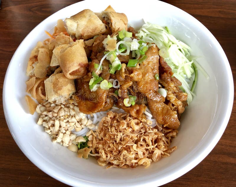 Vietnamese Rice Noodle bowl dish for lunch or dinner with spring rolls and grilled pork with peanuts and fried onions. Delicious Asian Meal. Vietnamese Rice Noodle bowl dish for lunch or dinner with spring rolls and grilled pork with peanuts and fried onions. Delicious Asian Meal