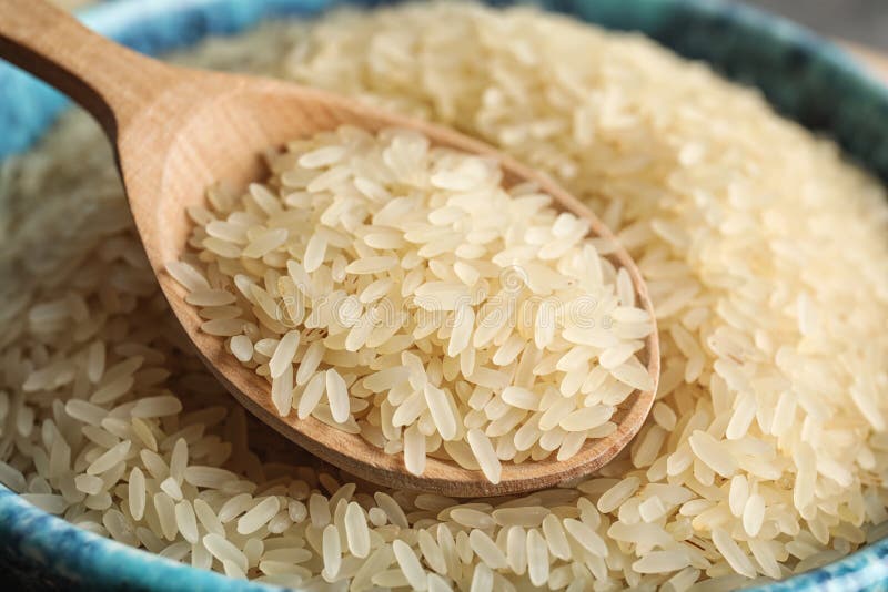 Cuenco y cuchara con arroz crudo imagen de archivo