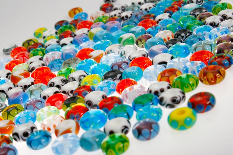 Multicolored round glass beads on a white surface. Multicolored round glass beads on a white surface.