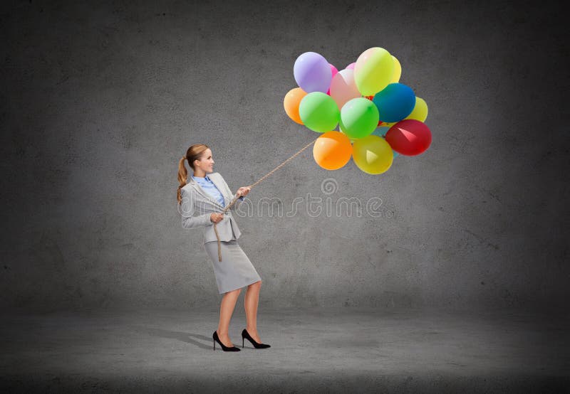 Cuerda de tracción sonriente de la empresaria con los globos fotografía de archivo Cuerda de tracción sonriente de la empresaria con los globos fotografía de archivo