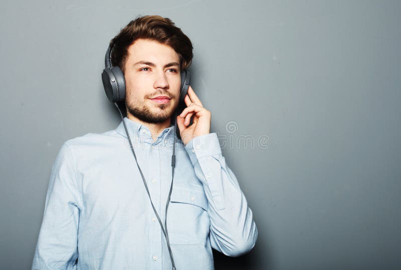Cuffie d'uso belle del giovane ed ascoltare la musica fotografia stock libera da diritti Cuffie d'uso belle del giovane ed ascoltare la musica fotografia stock libera da diritti