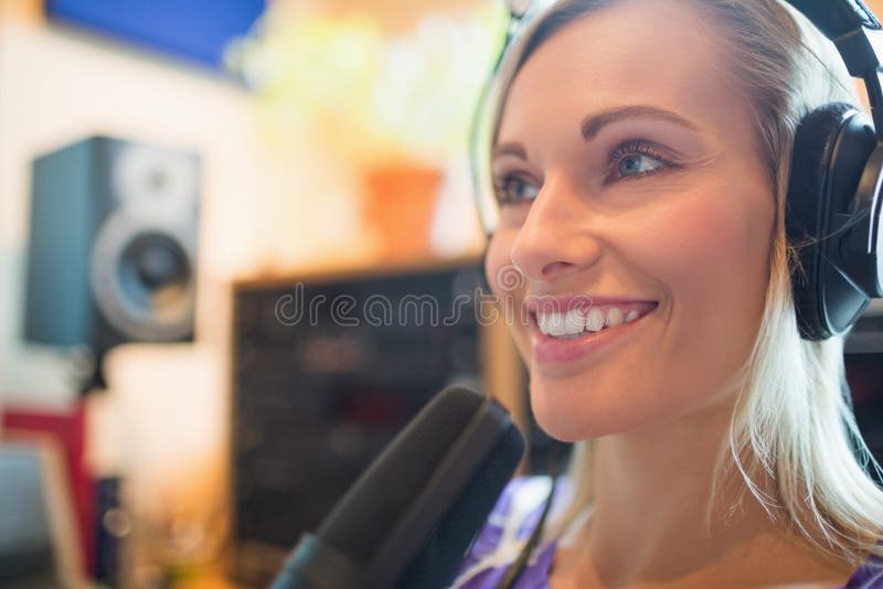 Cuffie d'uso giovane ospite radiofonico facendo uso dello studio del microfono fotografia stock Cuffie d'uso giovane ospite radiofonico facendo uso dello studio del microfono fotografia stock