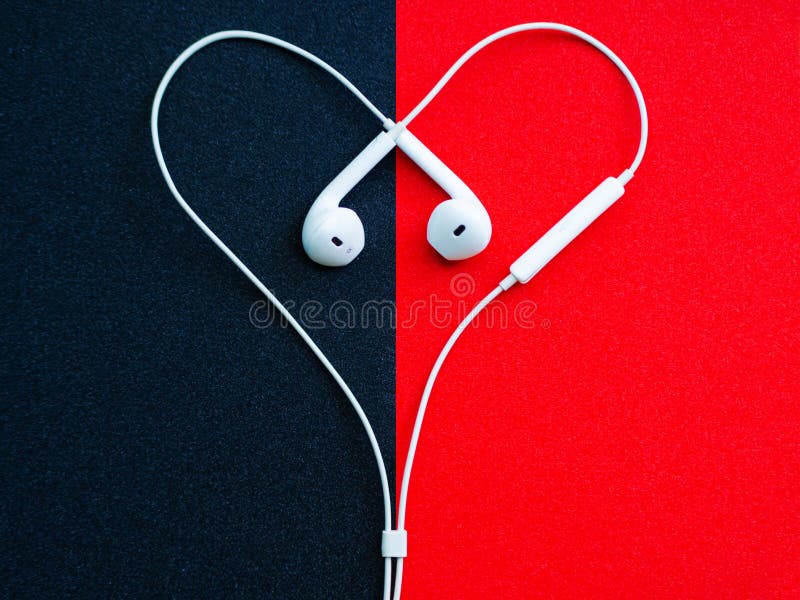 Cuffie metalliche bianche, cuffia avricolare in forma di cuore su un fondo nero-rosso immagini stock libere da diritti Cuffie metalliche bianche, cuffia avricolare in forma di cuore su un fondo nero-rosso immagini stock libere da diritti
