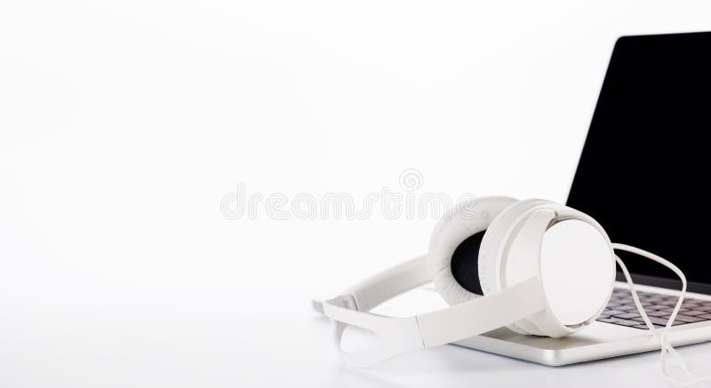 Cuffie poggiate su un laptop impostato su uno sfondo bianco luminoso immagine stock libera da diritti