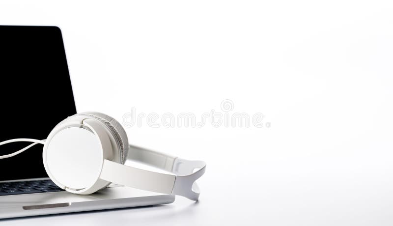 Cuffie poggiate su un laptop impostato su uno sfondo bianco luminoso. Cuffie posizionate su un laptop su uno sfondo bianco luminoso con ampio spazio di copia. L'illuminazione più elevata enfatizza un'estetica professionale e pulita ideale per la tecnologia o il lavoro