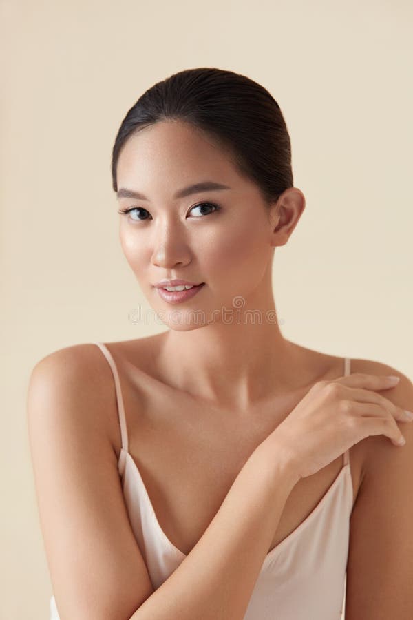 Skin Care. Beauty Portrait Of Asian Model. Ethnic Girl With Smooth Skin Touches Her Shoulder And Looking At Camera. Woman Enjoying Hydrated Skin And Perfect Body After Cosmetology Treatment. Skin Care. Beauty Portrait Of Asian Model. Ethnic Girl With Smooth Skin Touches Her Shoulder And Looking At Camera. Woman Enjoying Hydrated Skin And Perfect Body After Cosmetology Treatment