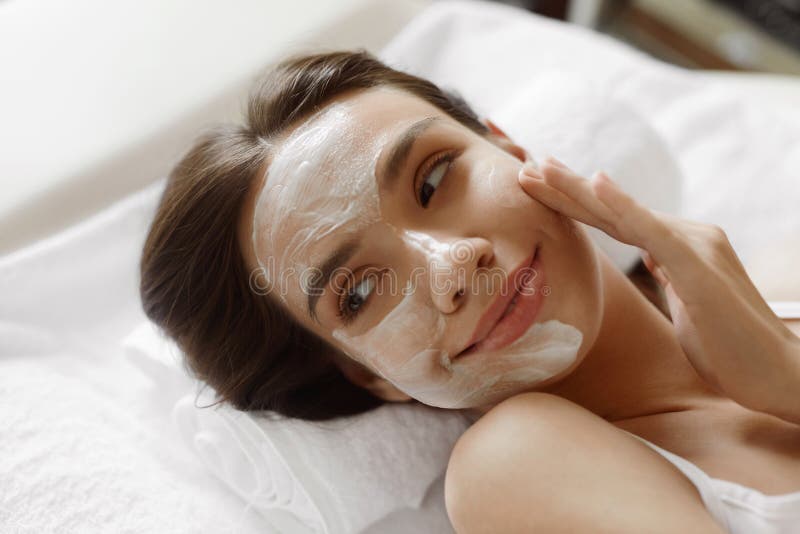 Cuidado de piel de la cara Mujer hermosa con la máscara cosmética facial en el balneario