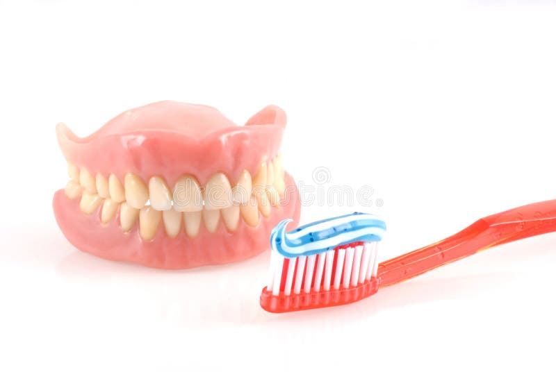 Dentures and toothbrush with toothpaste isolated on white. Dentures and toothbrush with toothpaste isolated on white.