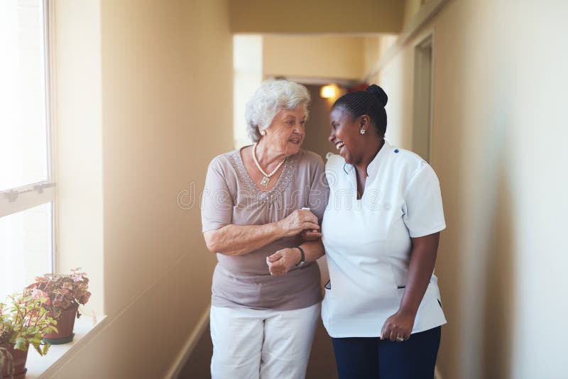 Cuidador femenino feliz y mujer mayor que caminan junto