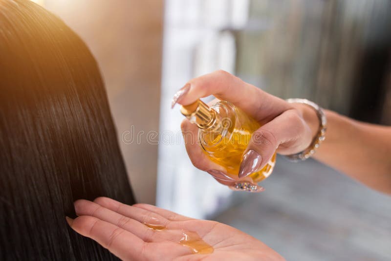 Cuidados capilares no salão de beleza moderno dos termas a mulher do cabeleireiro aplica uma máscara ou um óleo no cabelo do clie imagem de stock royalty free Cuidados capilares no salão de beleza moderno dos termas a mulher do cabeleireiro aplica uma máscara ou um óleo no cabelo do clie imagem de stock royalty free
