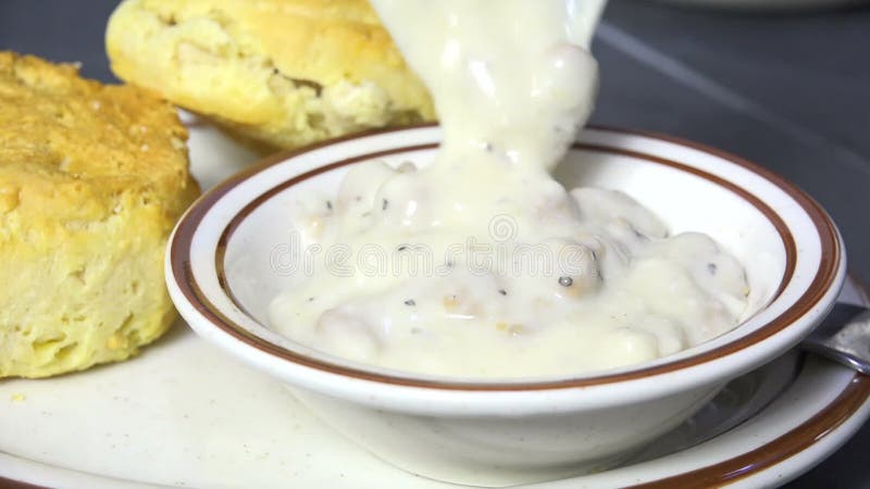 Cuiller la sauce country dans un bol avec des biscuits frais cuits