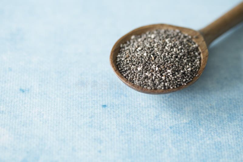 Cuillère en bois avec des graines de chia, fond bleu L'espace pour le texte image libre de droits Cuillère en bois avec des graines de chia, fond bleu L'espace pour le texte image libre de droits