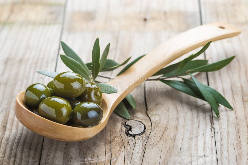 Cuillère en bois avec les olives et l'huile