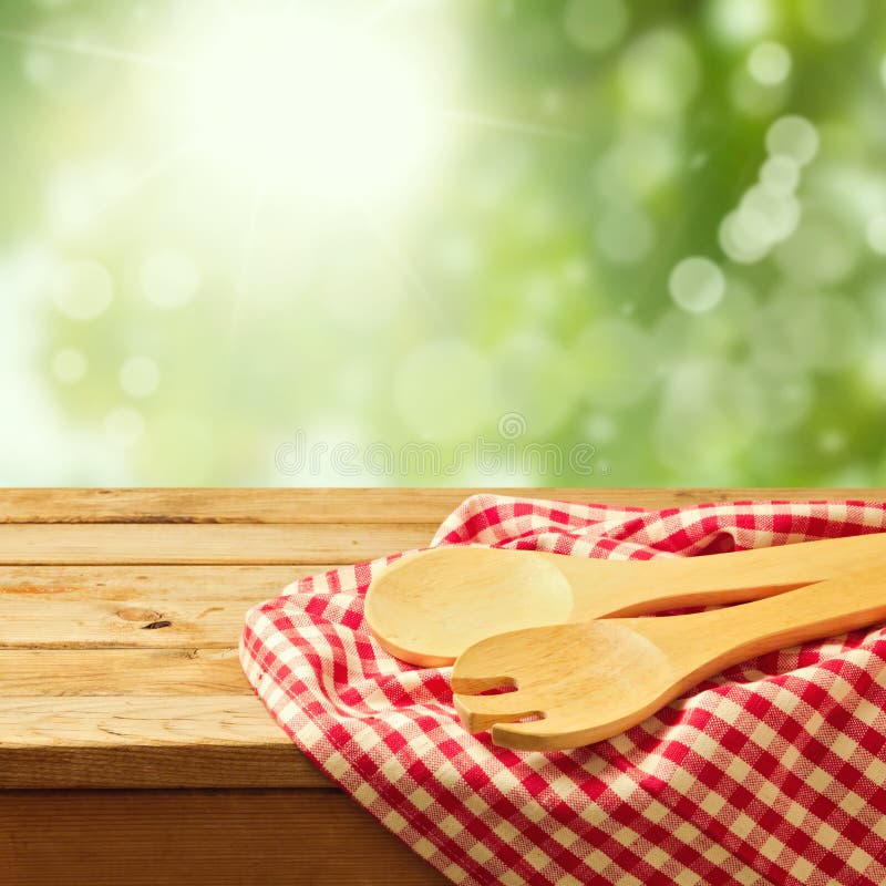 Wooden spoon on tablecloth over garden bokeh background. Wooden spoon on tablecloth over garden bokeh background