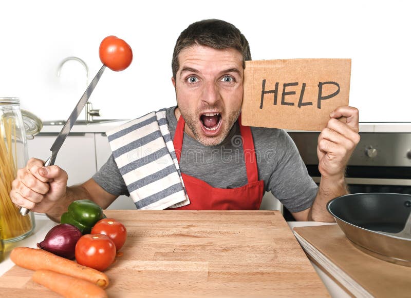 Cuisine de jeune homme à la maison dans le tablier de cuisinier désespéré en faisant cuire l'effort images stock Cuisine de jeune homme à la maison dans le tablier de cuisinier désespéré en faisant cuire l'effort images stock
