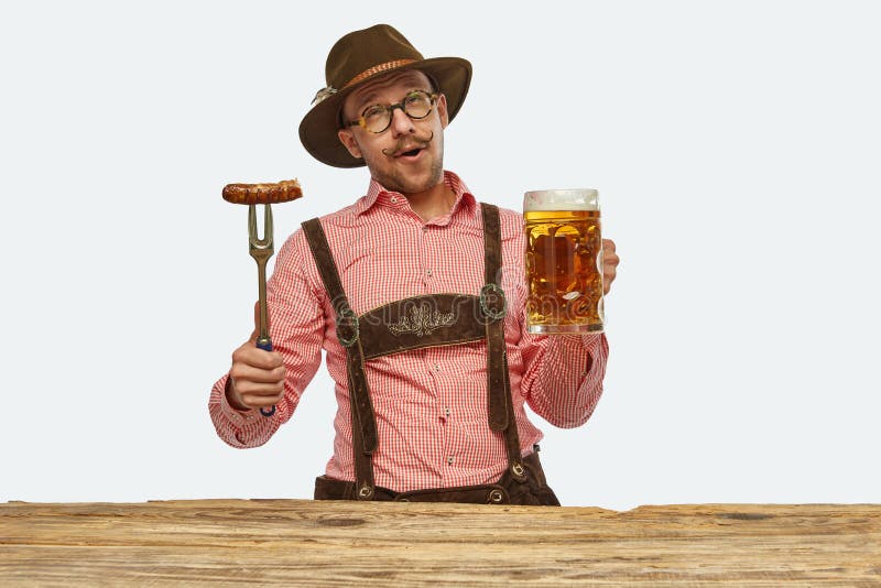 Tasty cuisine. Delightful man wearing traditional fest Bavarian or German outfit with huge beer mug tasting fried sausage. Concept of Oktoberfest, traditions, drinks and food. Copy space for ad. Tasty cuisine. Delightful man wearing traditional fest Bavarian or German outfit with huge beer mug tasting fried sausage. Concept of Oktoberfest, traditions, drinks and food. Copy space for ad