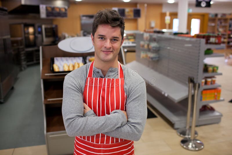 Assertive cook smiling at the camera in front of his bakery. Assertive cook smiling at the camera in front of his bakery