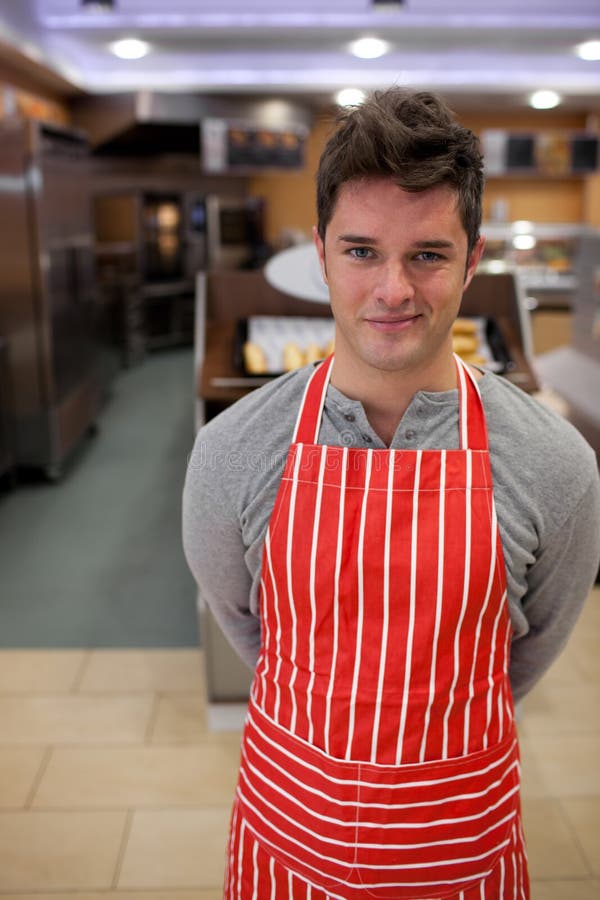 Confident cook smiling at the camera in front of his bakery. Confident cook smiling at the camera in front of his bakery