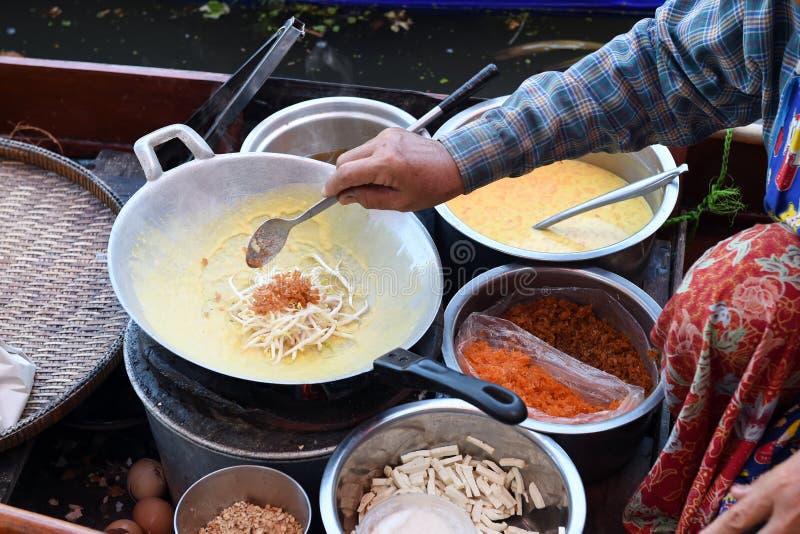 Cuisinier de vendeur de femmes l'omelette thaïlandaise avec des légumes sur le bateau au marché de l'eau photos stock Cuisinier de vendeur de femmes l'omelette thaïlandaise avec des légumes sur le bateau au marché de l'eau photos stock