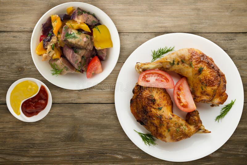Chicken thigh with vegetables salad on a wooden background. chicken leg on a plate. Chicken thigh with vegetables salad on a wooden background. chicken leg on a plate