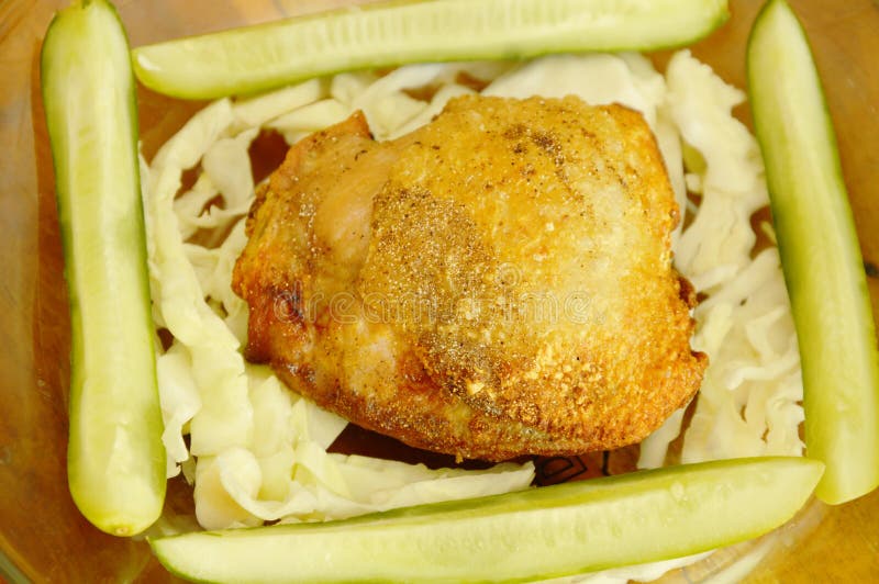 fried chicken thigh dressing salt and pepper with vegetable on glass plate. fried chicken thigh dressing salt and pepper with vegetable on glass plate