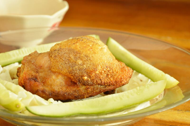 fried chicken thigh dressing salt and pepper with vegetable on glass plate. fried chicken thigh dressing salt and pepper with vegetable on glass plate