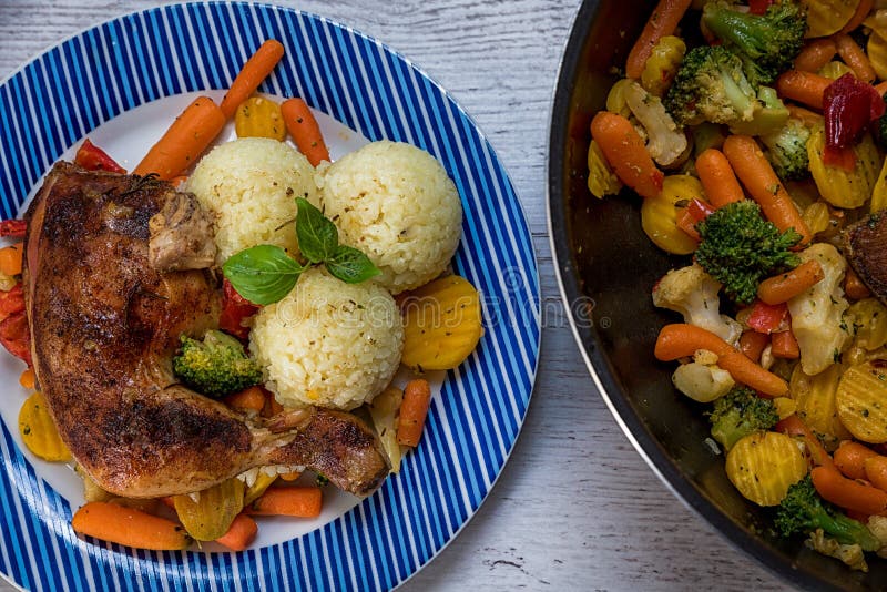 Roasted chicken thigh, vegetables as a supplement, tasty ripe rice with basil, prepared on the table. Roasted chicken thigh, vegetables as a supplement, tasty ripe rice with basil, prepared on the table