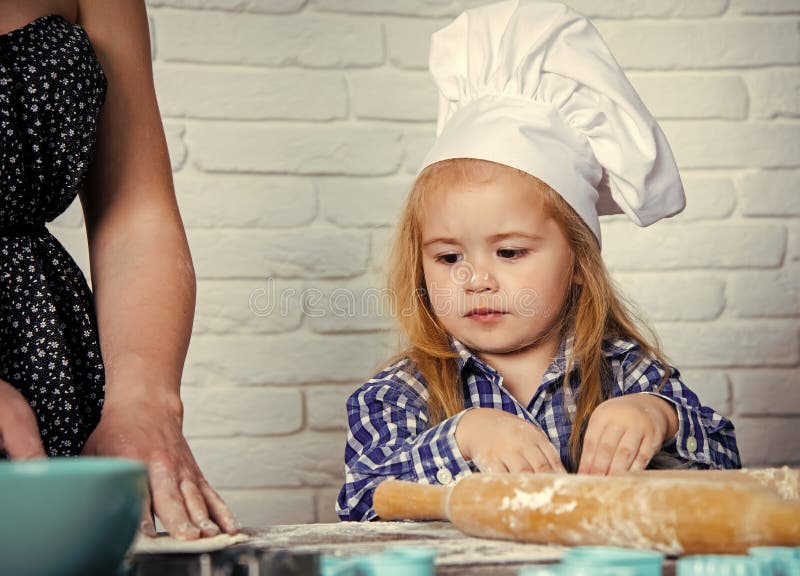 Cuisson de la formation Cuisinier d'enfant dans la mère de aide de chapeau de chef images stock Cuisson de la formation Cuisinier d'enfant dans la mère de aide de chapeau de chef images stock