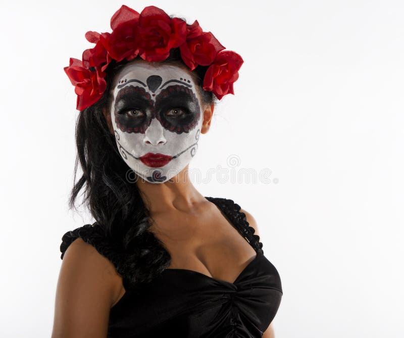 Close up of a beautiful, sexy, young woman with red roses in her hair and sugar skull makeup isolated on a white background. Close up of a beautiful, sexy, young woman with red roses in her hair and sugar skull makeup isolated on a white background.