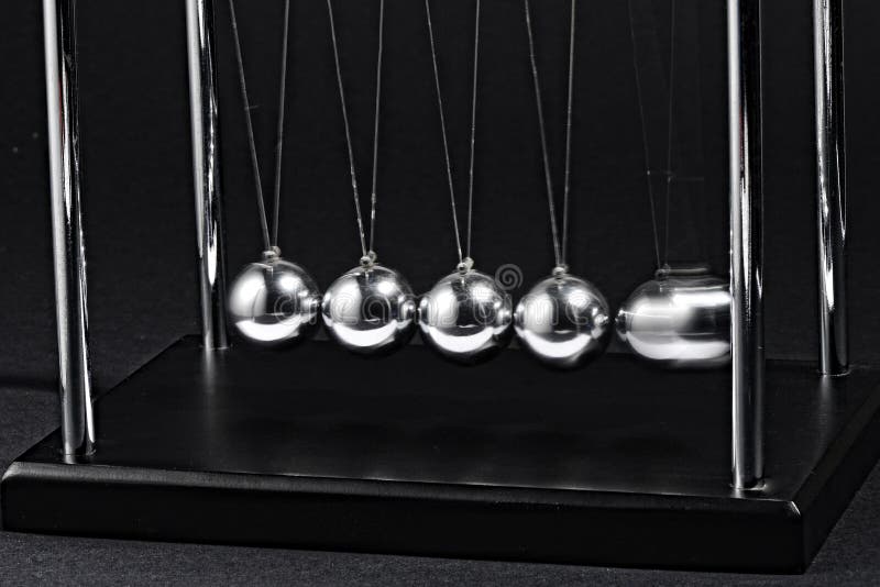 Newtons cradle an executive desktop puzzle with five suspended steel balls in a frame used to demonstrate perpetual motion and conservation of momentum based on physics. Newtons cradle an executive desktop puzzle with five suspended steel balls in a frame used to demonstrate perpetual motion and conservation of momentum based on physics