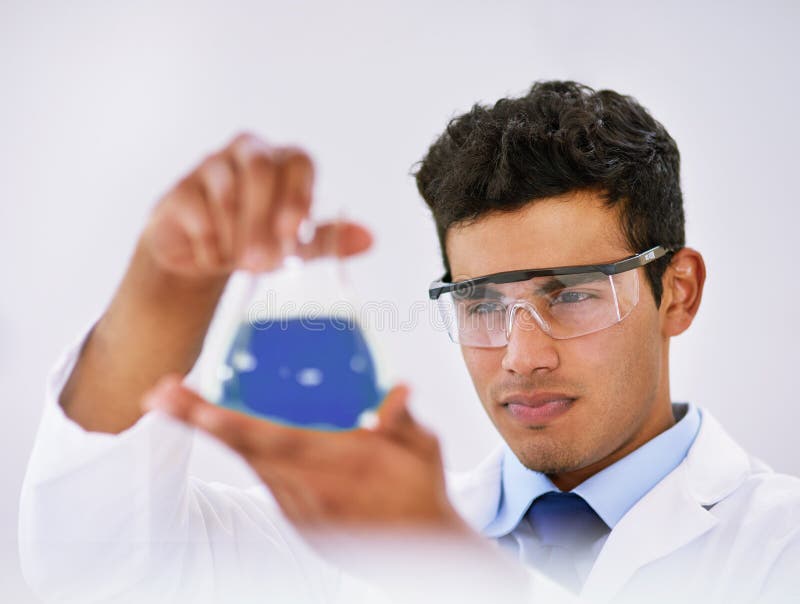 The Culmination of Long Experimenting. a Lab Technician Examining a Beaker of Blue Liquid while