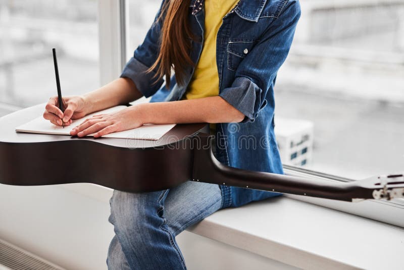Cultiver anonyme preteen guitariste prenant des notes dans copybook pendant la classe photographie stock