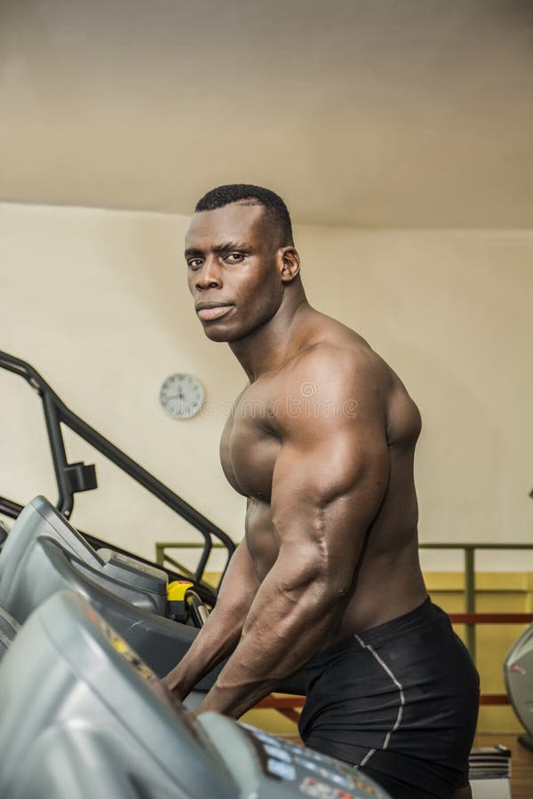 Culturista maschio nero muscolare che si esercita sulla pedana mobile in palestra immagini stock Culturista maschio nero muscolare che si esercita sulla pedana mobile in palestra immagini stock
