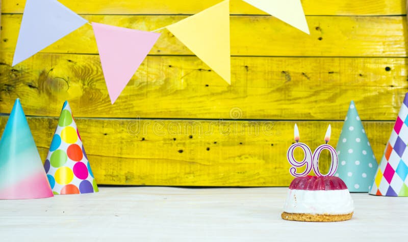 Colorful card happy birthday with festive decorations with cake and burning candles. Copy space. Beautiful happy birthday background on the background of yellow boards with a number of candles number 90. Colorful card happy birthday with festive decorations with cake and burning candles. Copy space. Beautiful happy birthday background on the background of yellow boards with a number of candles number 90