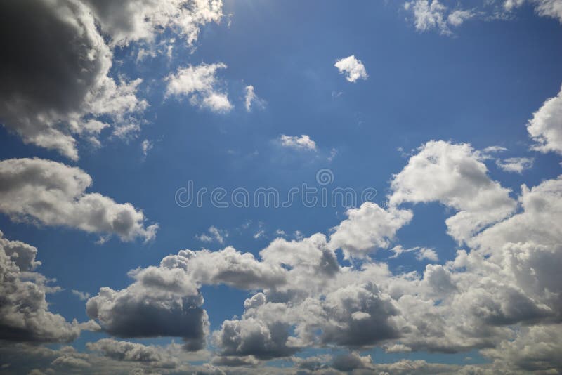 Cumulonimbus clouds floating overhead in the blue sky lightened by sunrays. Cumulonimbus clouds floating overhead in the blue sky lightened by sunrays