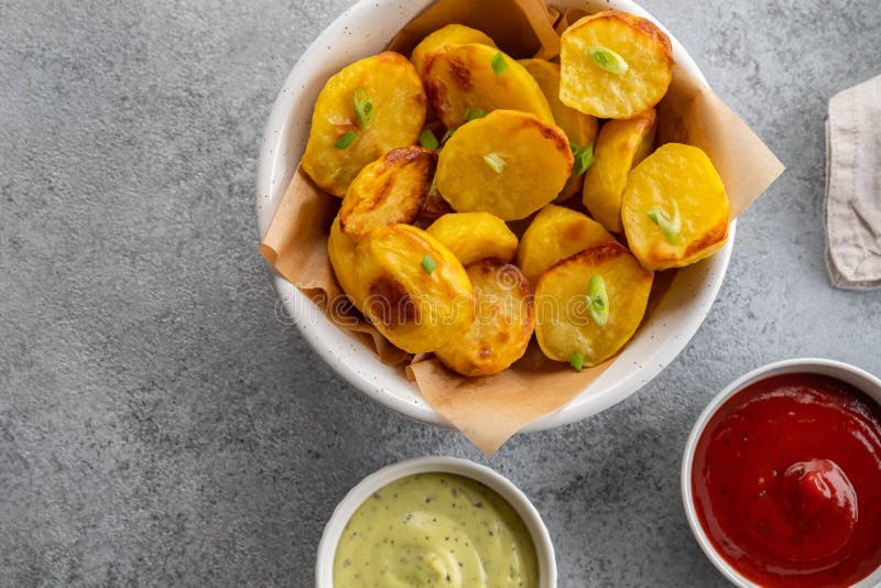 Cunei al forno della patata con formaggio ed erbe e salsa al pomodoro su fondo grigio - vegano di verdure organico casalingo fotografie stock libere da diritti Cunei al forno della patata con formaggio ed erbe e salsa al pomodoro su fondo grigio - vegano di verdure organico casalingo fotografie stock libere da diritti