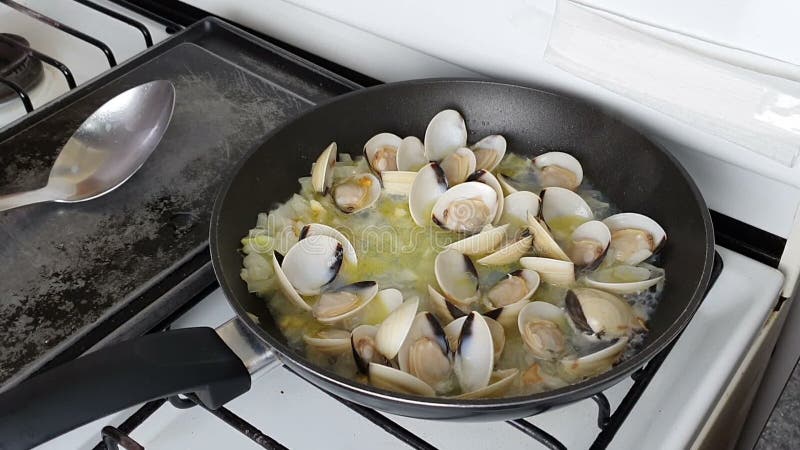 Cuoca cozze per cucinare in padella. cuoco che frigge cozze con cozze di cova