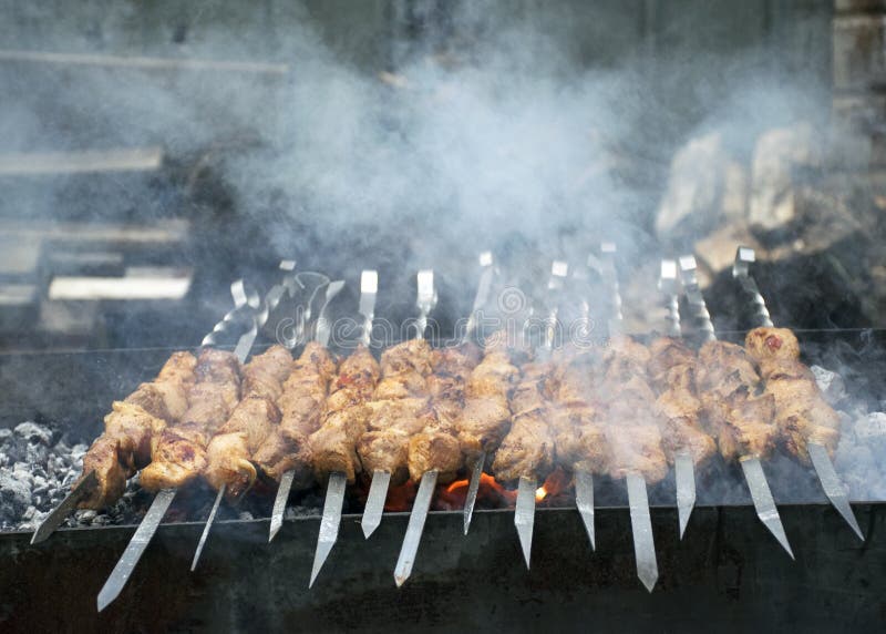 Cuochi della carne sui carboni caldi nel fumo Picnic in natura fotografia stock libera da diritti Cuochi della carne sui carboni caldi nel fumo Picnic in natura fotografia stock libera da diritti