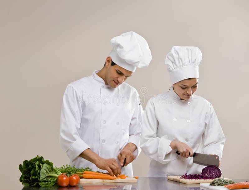 Cuochi unici in toques che preparano e che tagliano alimento a pezzi fotografie stock libere da diritti Cuochi unici in toques che preparano e che tagliano alimento a pezzi fotografie stock libere da diritti