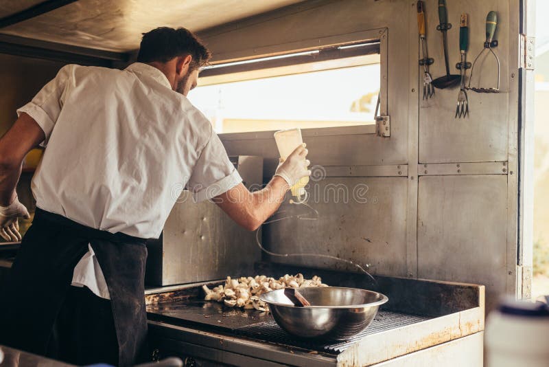 Cuoco maschio che prepara alimento sul camion immagine stock libera da diritti Cuoco maschio che prepara alimento sul camion immagine stock libera da diritti