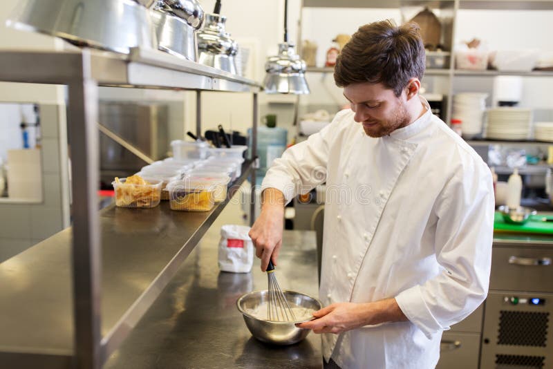 Cuoco unico maschio felice che cucina alimento alla cucina del ristorante immagini stock Cuoco unico maschio felice che cucina alimento alla cucina del ristorante immagini stock