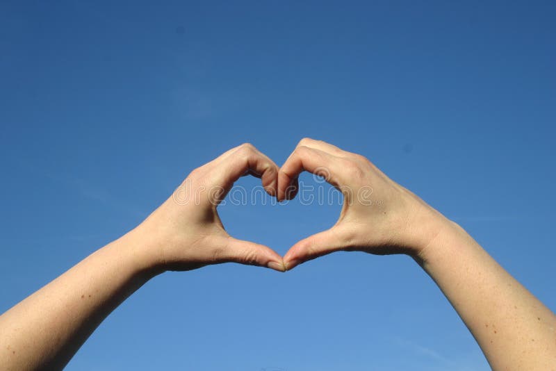 Cuore di amore con le mani in cielo blu immagini stock