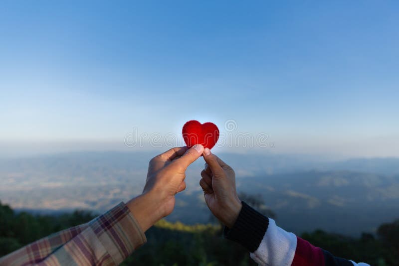 Cuore rosso in mani delle coppie dell'amante sul fondo della sfuocatura fotografia stock