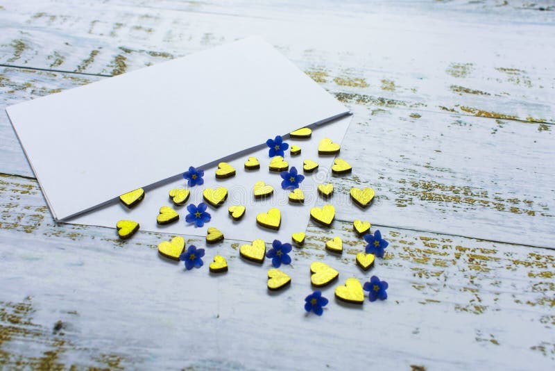 Cuori dorati e piccoli fiori blu in una busta su un fondo lilla Giorno del `s del biglietto di S regalo di concetto di amore, mes immagini stock Cuori dorati e piccoli fiori blu in una busta su un fondo lilla Giorno del `s del biglietto di S regalo di concetto di amore, mes immagini stock