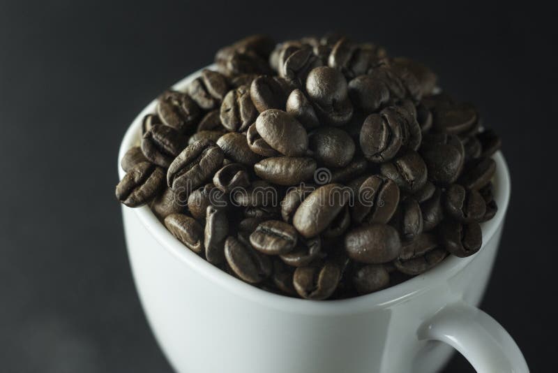 Cup of Black Coffee with Foam on Background of Roasted Coffee Beans